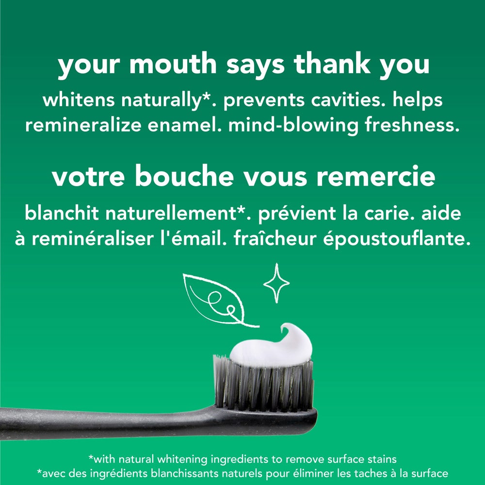 A close-up of a toothbrush with a dollop of white toothpaste, set against a green background. Above the toothbrush is a white leaf illustration. Text lists the toothpaste's benefits: "whitens naturally, prevents cavities, helps remineralize enamel, mind-blowing freshness" in both English and French.